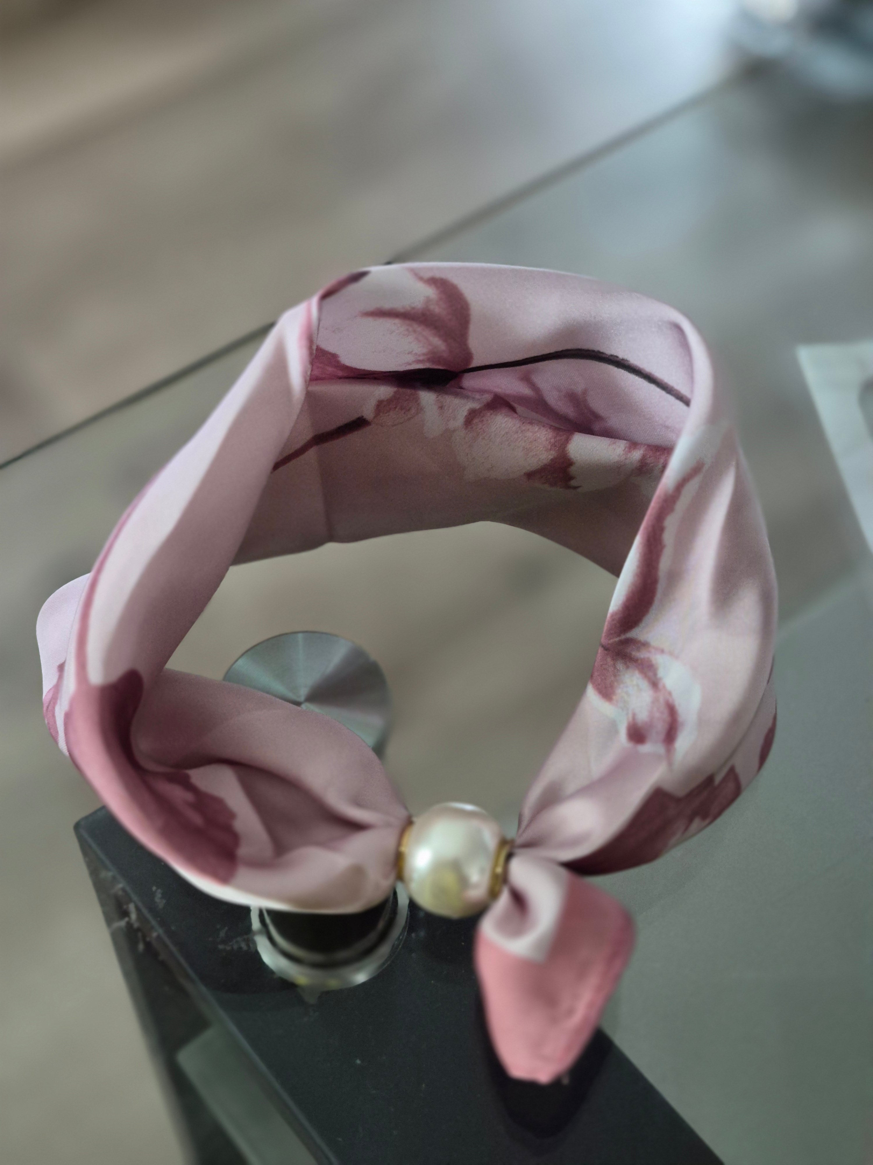 Aria Floral Silk-Feeling Neckerchief Scarf with a Pearl Slide displayed on a glass table.