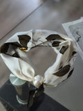 Aria Floral Silk-Feeling Neckerchief Scarf with a Pearl Slide elegantly displayed on a glass surface.