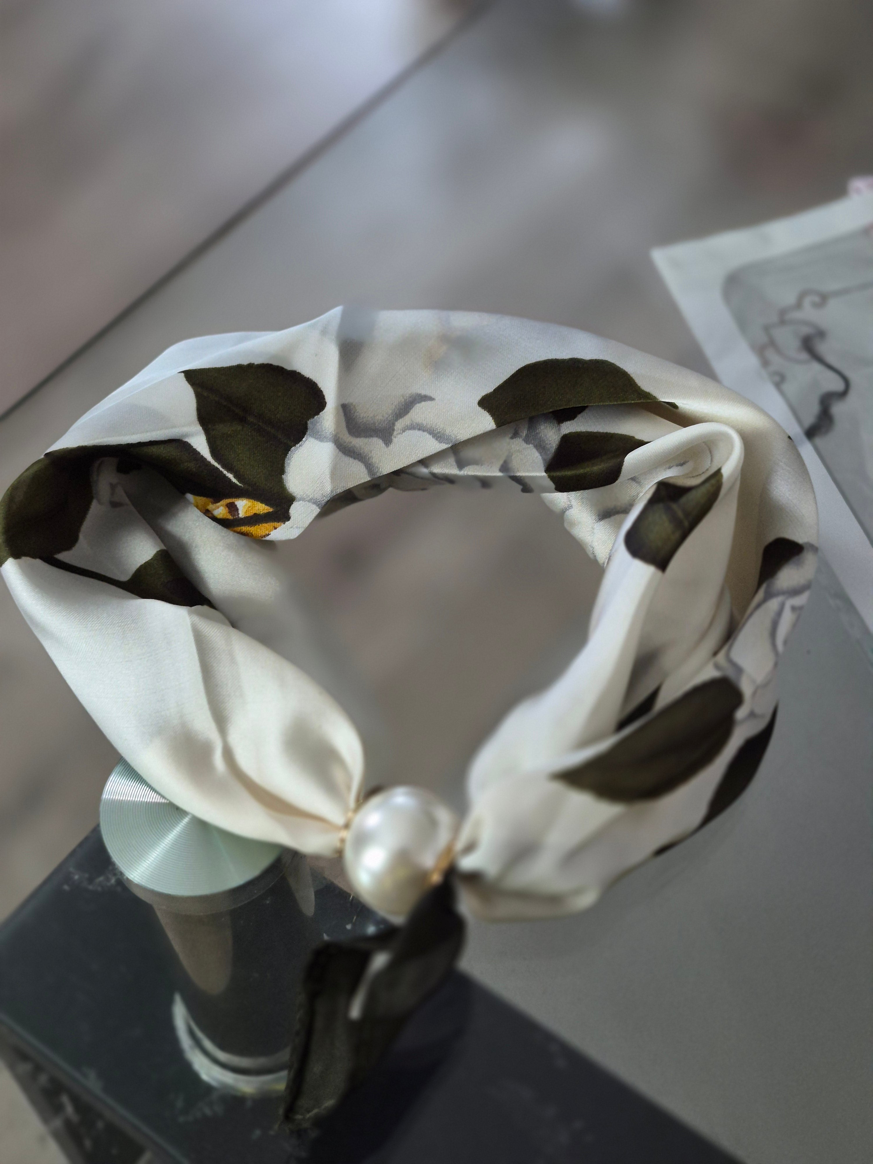 Aria Floral Silk-Feeling Neckerchief Scarf with a Pearl Slide elegantly displayed on a glass surface.